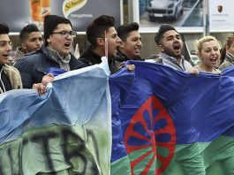 Grupo de jóvenes gitanos llevando la bandera del Pueblo Gitano en una manifestación / Georgi Licovski (EFE)