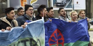 Grupo de jóvenes gitanos llevando la bandera del Pueblo Gitano en una manifestación / Georgi Licovski (EFE)